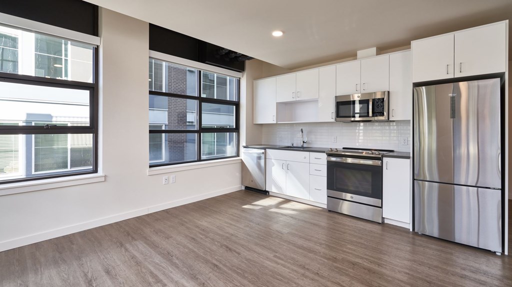 A modern kitchen with stainless steel appliances and wooden flooring.