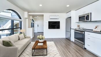 A modern kitchen with a breakfast bar and a living room area with a sofa.