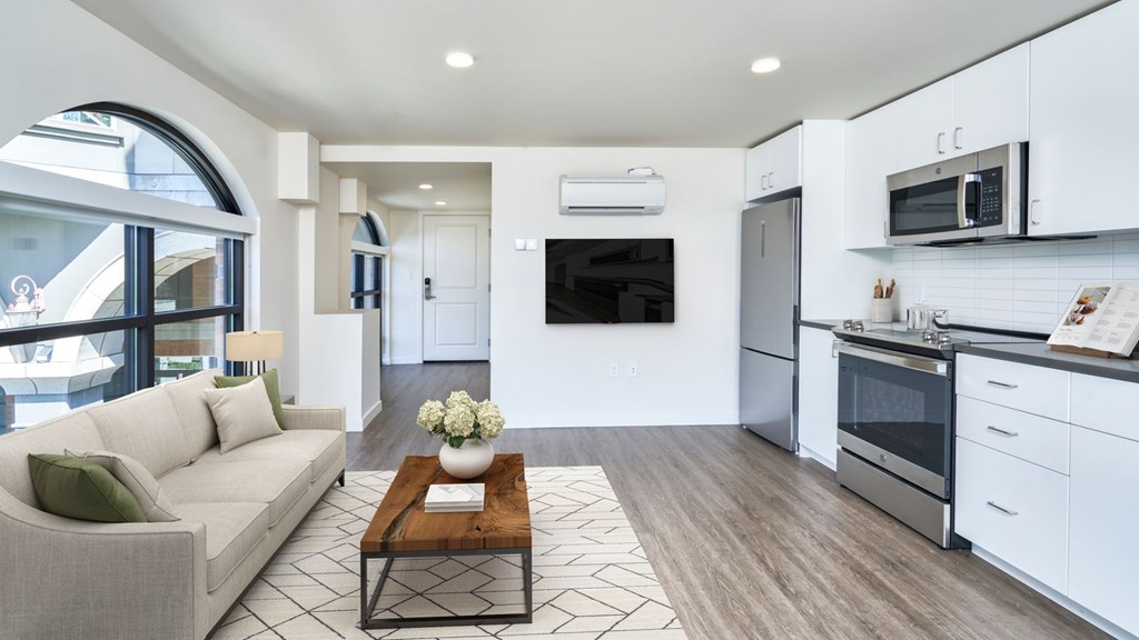 A modern kitchen with a breakfast bar and a living room area with a sofa.