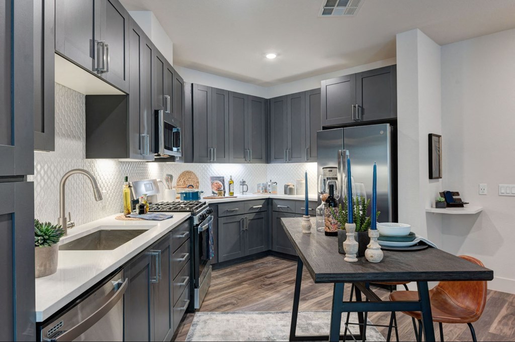 a kitchen with gray cabinets and stainless steel appliances and a table at Scottsdale Grand, Scottsdale, AZ, 85260