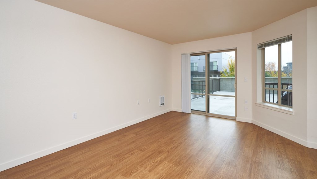 Empty room with wooden floors and sliding glass doors.