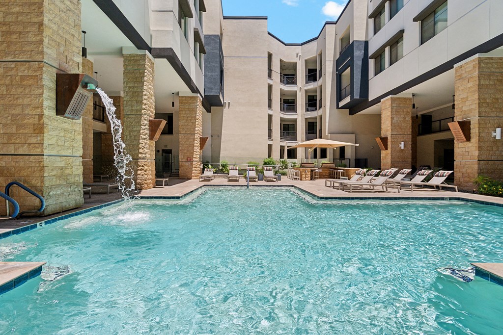 a swimming pool with chairs and a building in the background