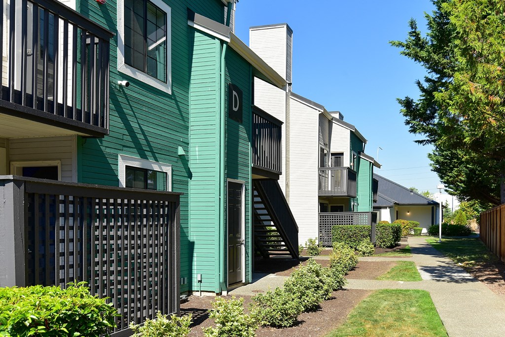 a row of green and white apartment buildings with a sidewalk