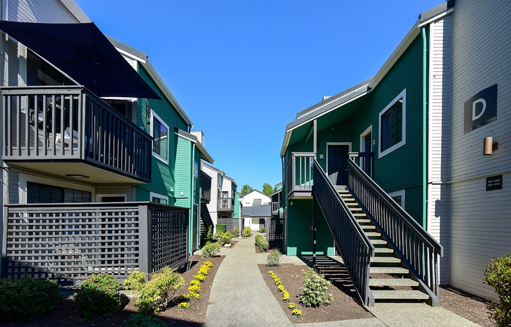 a row of green houses with stairs and a sidewalk