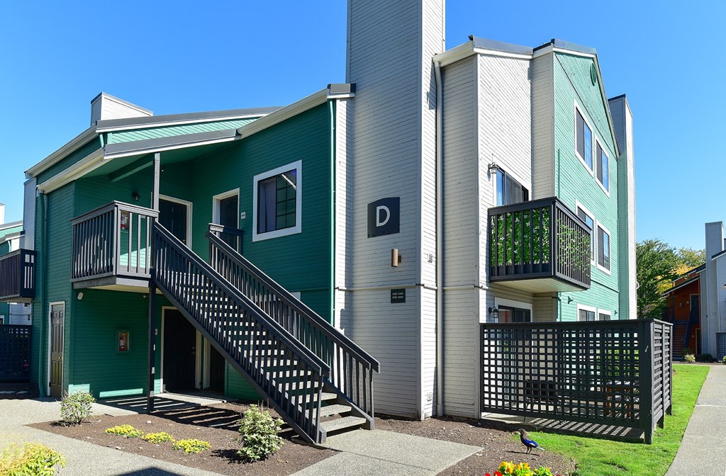 the front of a green house with stairs and a porch