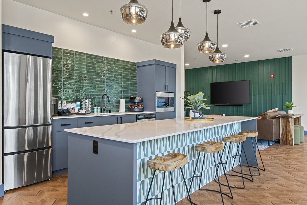 a kitchen with a large island with stools and a refrigerator