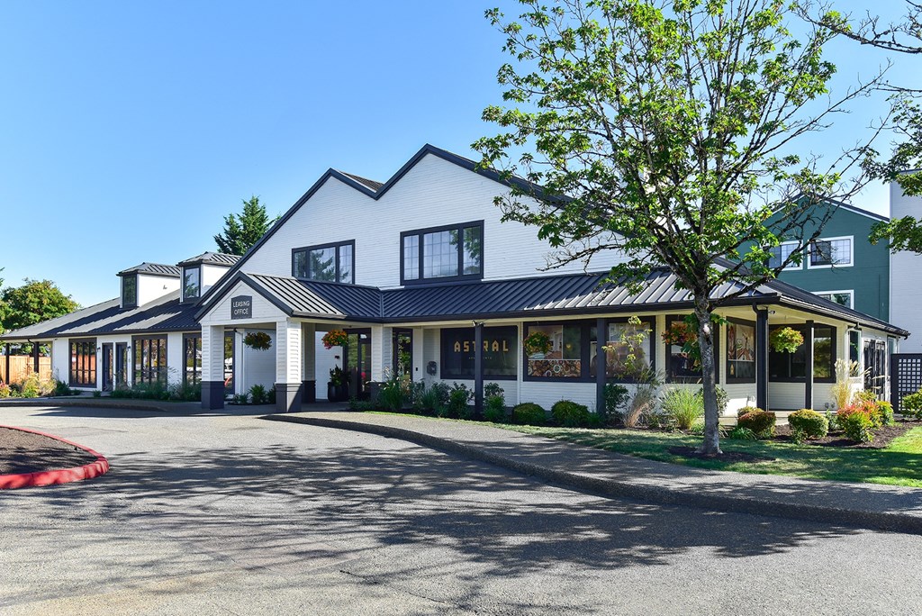 the exterior of a white house with a driveway and a tree