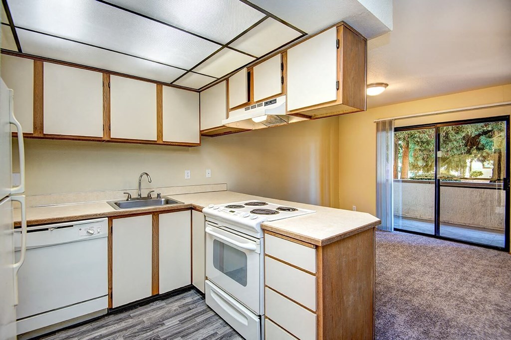 A kitchen with white appliances and wooden cabinets. at Autumn Village, Milton, WA, 98354