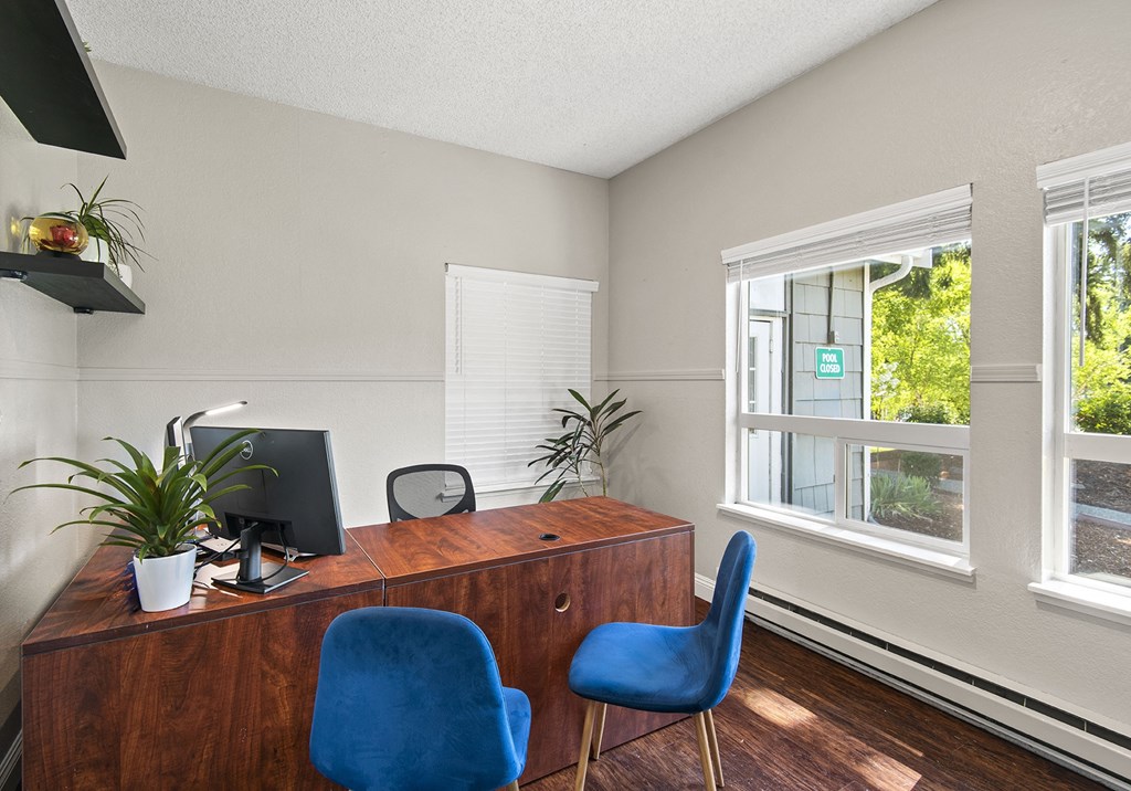 a desk with a computer monitor and two blue chairs