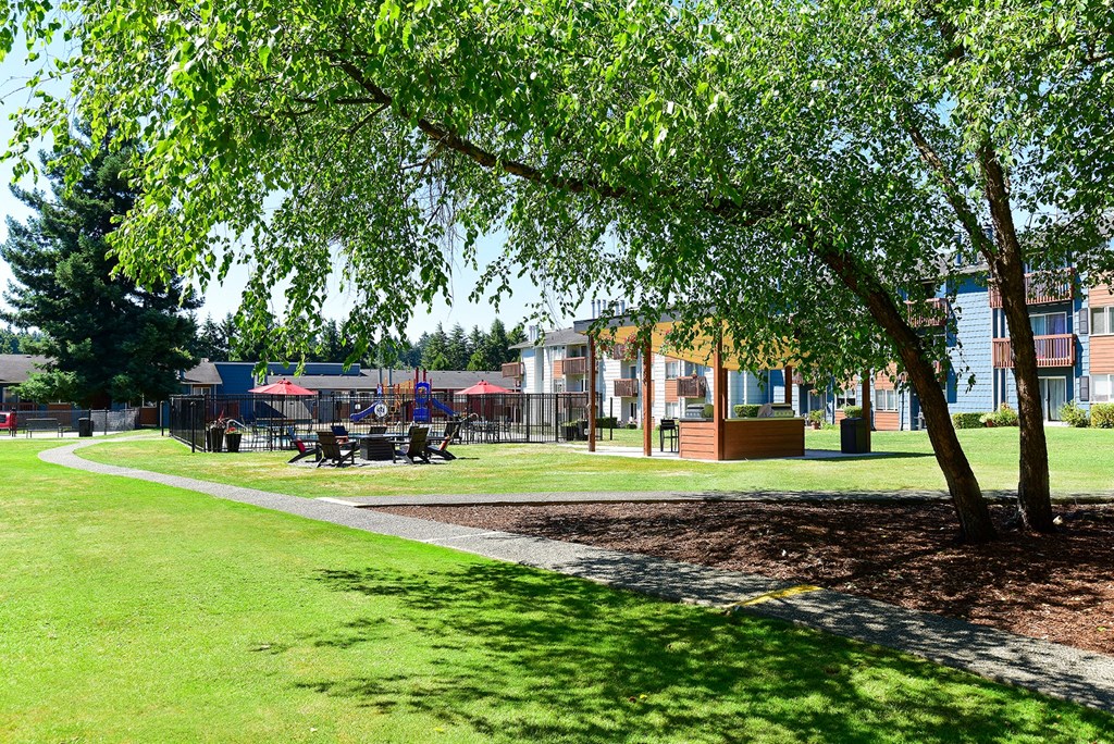 a grassy area with trees and buildings in the background