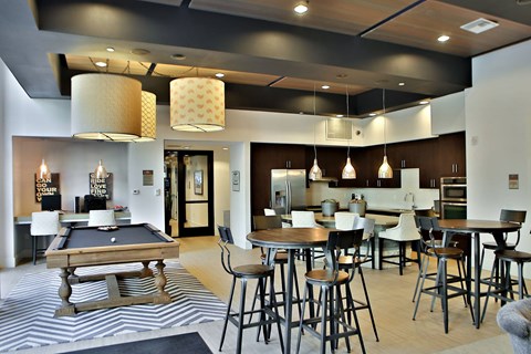A modern kitchen with a pool table in the middle.