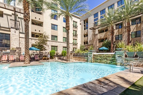 A swimming pool surrounded by palm trees and lounge chairs.