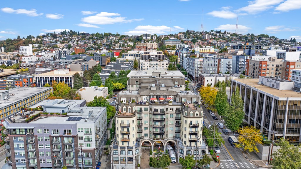 A cityscape with a mix of modern and older buildings, a clear sky, and a road with moving vehicles.