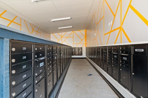 A long hallway with a series of black lockers with numbers on them.