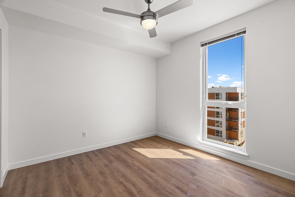 an empty room with a window and a ceiling fan