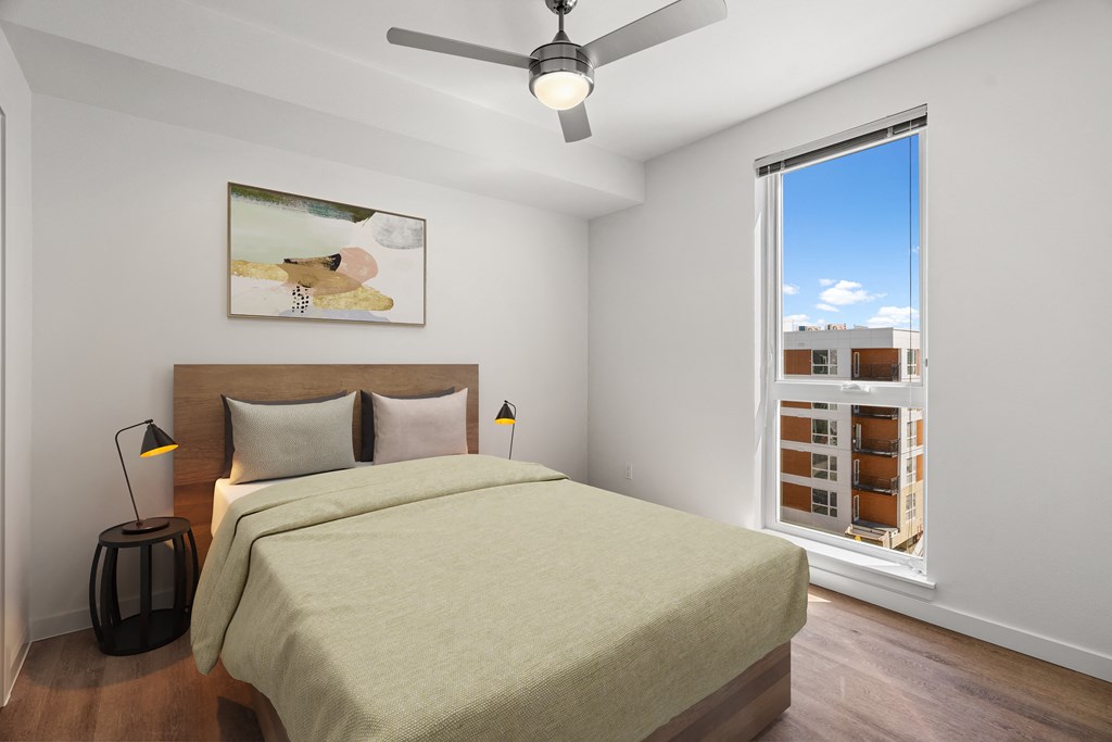 a bedroom with a bed and a large window and a ceiling fan