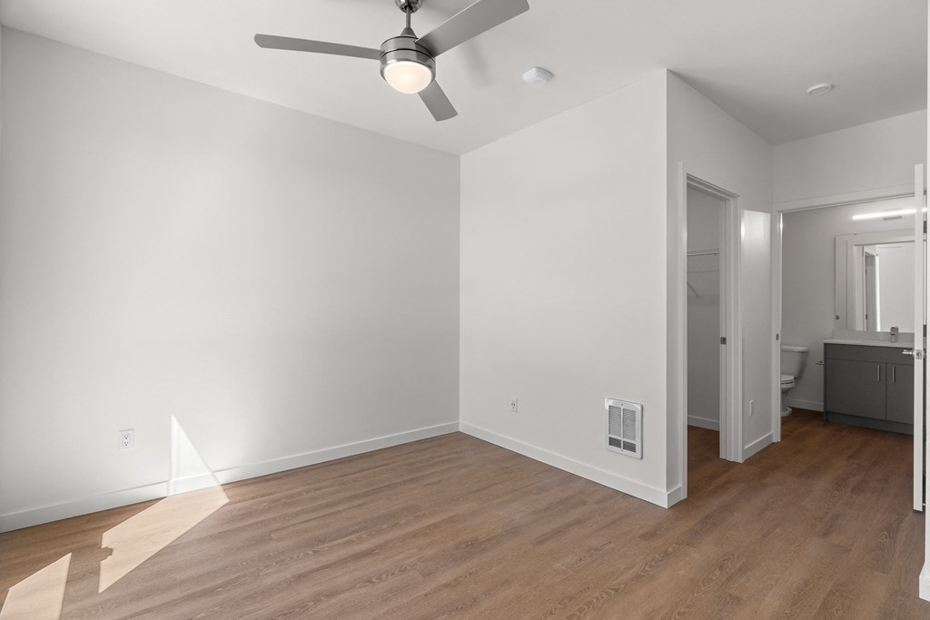 an empty living room with white walls and a ceiling fan