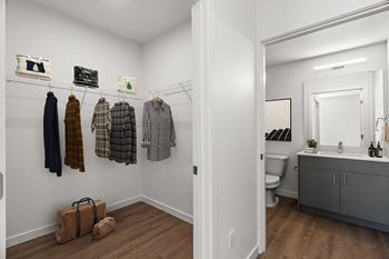 a closet with clothes hanging on the wall and a bathroom with a toilet