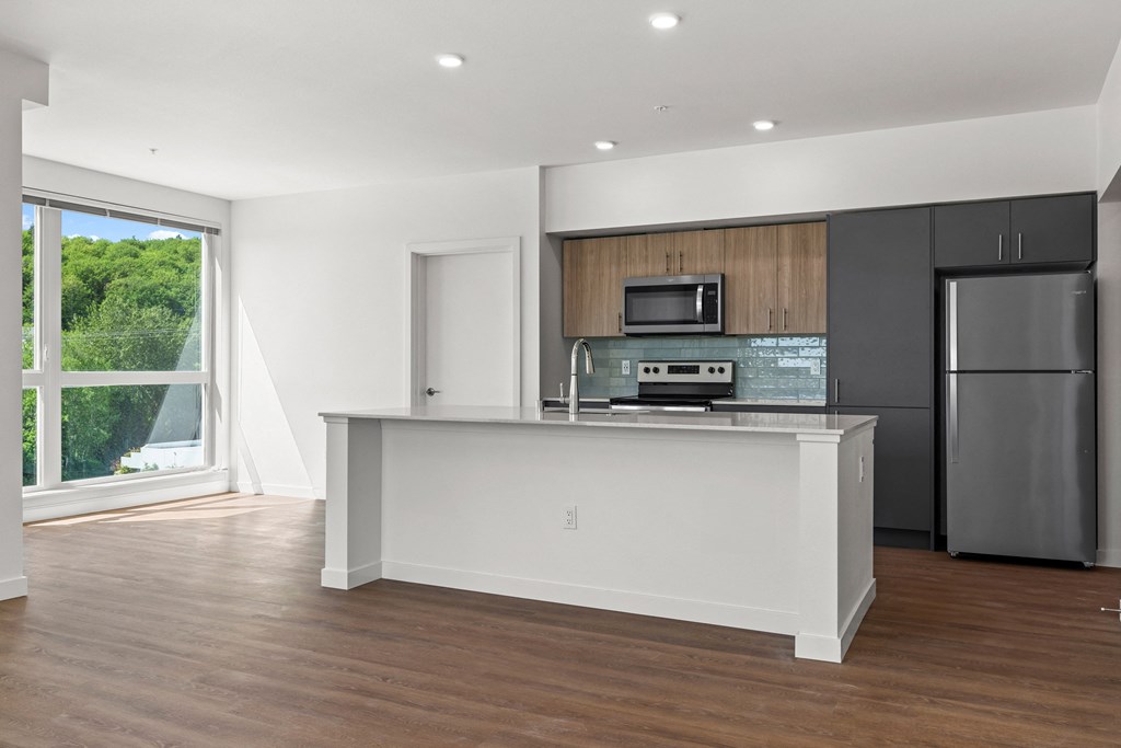 a kitchen with a large island and a stainless steel refrigerator