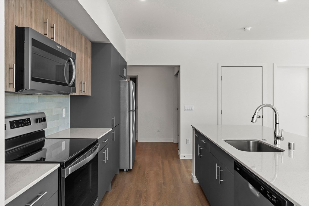 an empty kitchen with black counter tops and stainless steel appliances