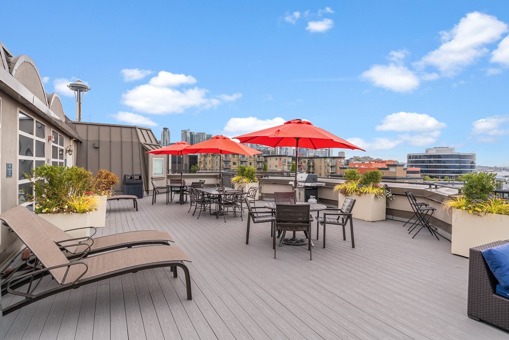 A rooftop patio with red umbrellas and chairs.