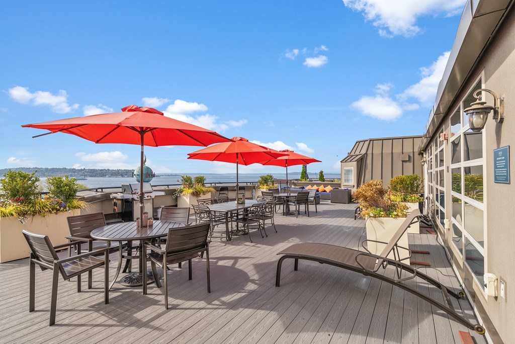 A patio with red umbrellas and wooden flooring.