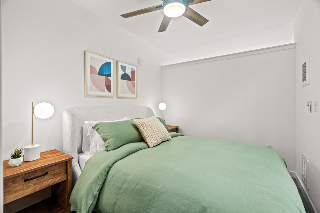 a bedroom with a green bed and a ceiling fan