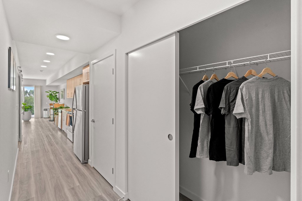 a hallway closet open with shirts hanging