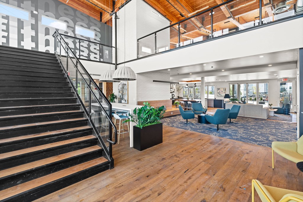 the lobby of a building with a staircase and a lobby area with chairs and tables