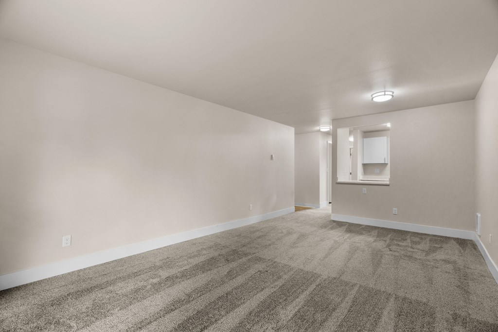 an empty living room with carpet and white walls