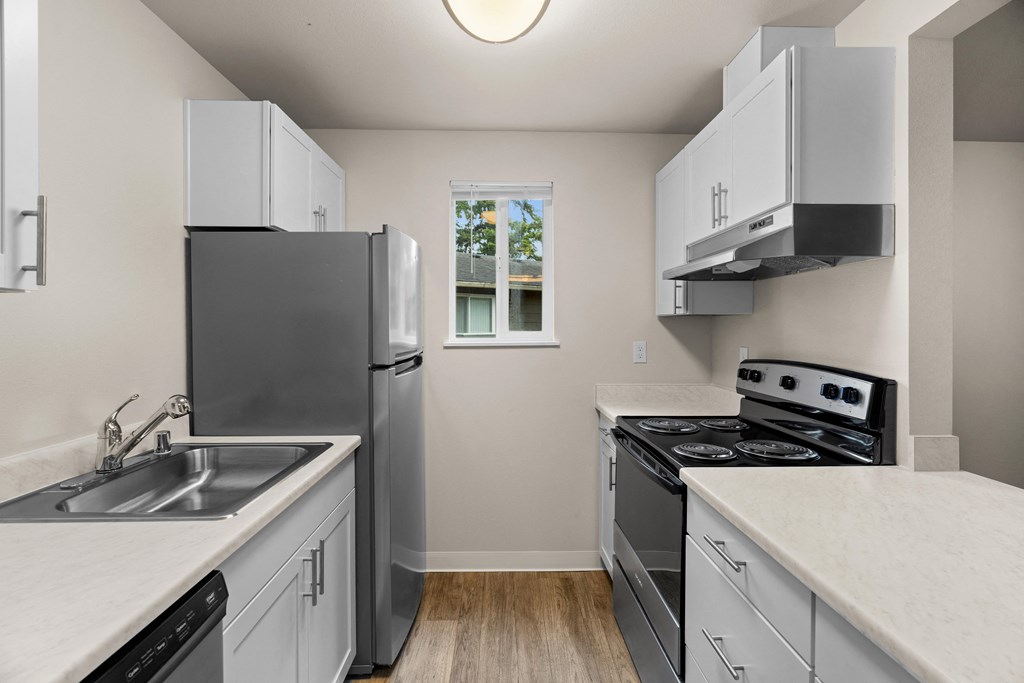 an empty kitchen with white cabinets and stainless steel appliances