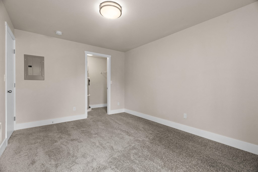 an empty living room with carpet and a door to a hallway
