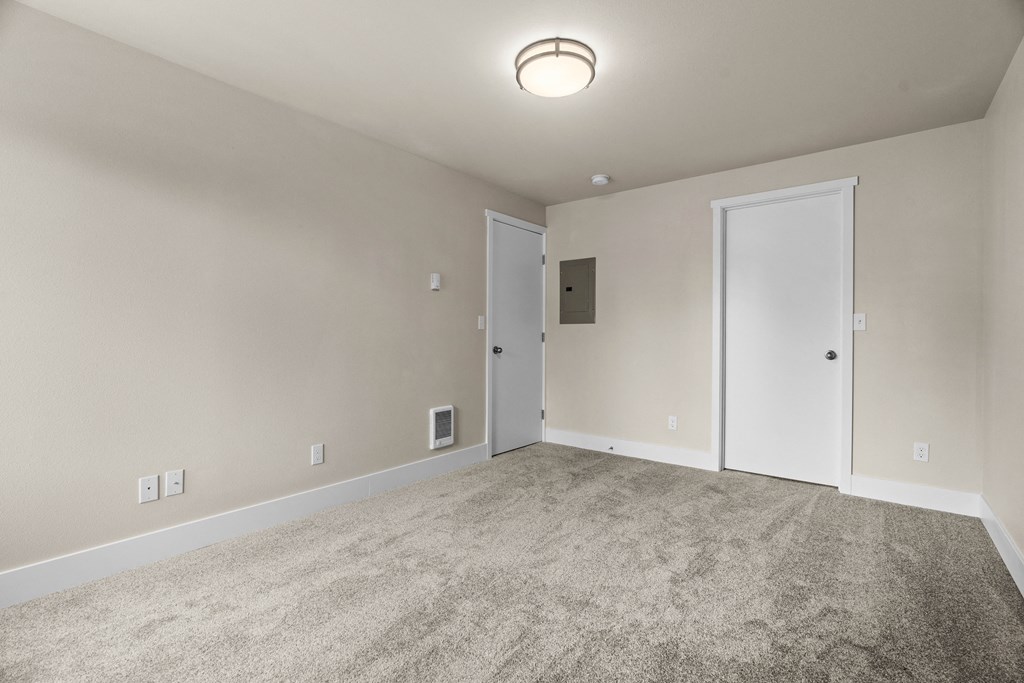 an empty living room with carpet and a door to a bedroom