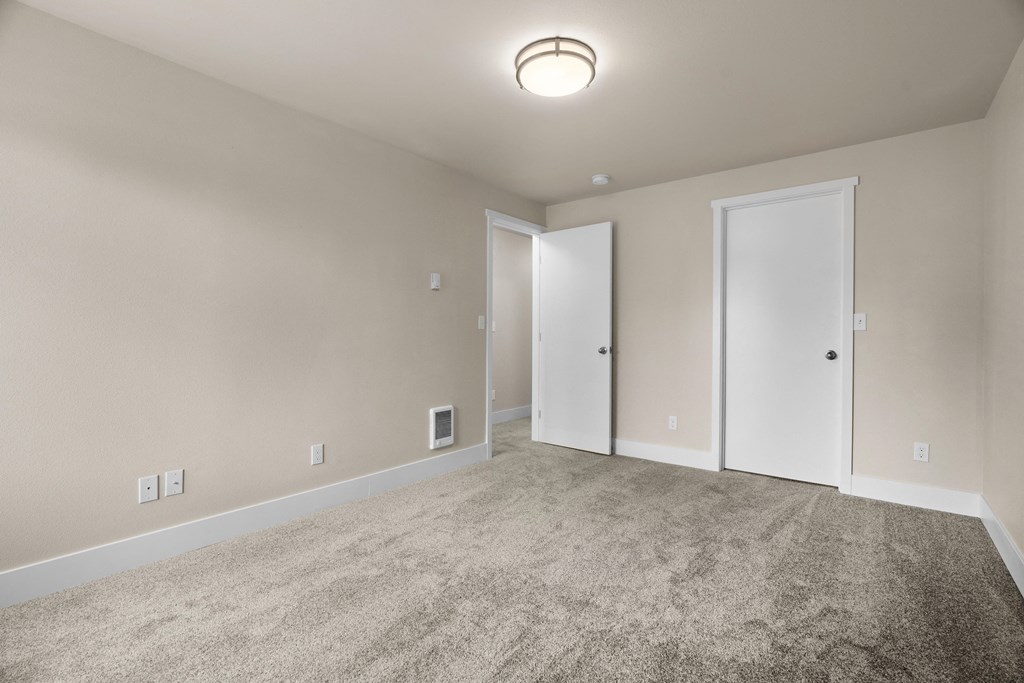 an empty living room with carpet and a door to a bedroom