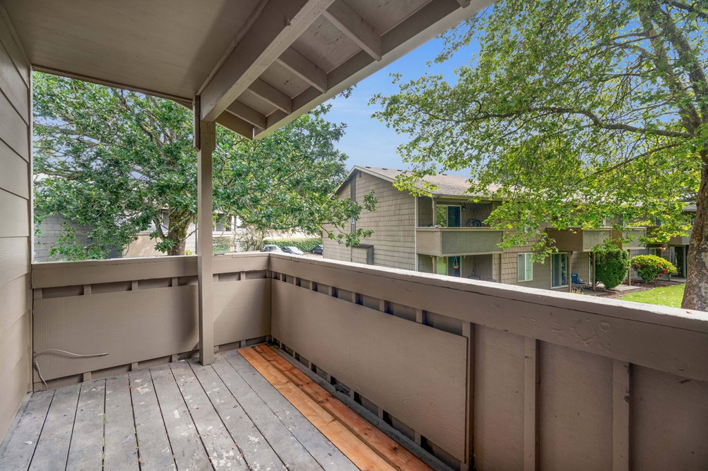 a large deck with trees and a house in the background