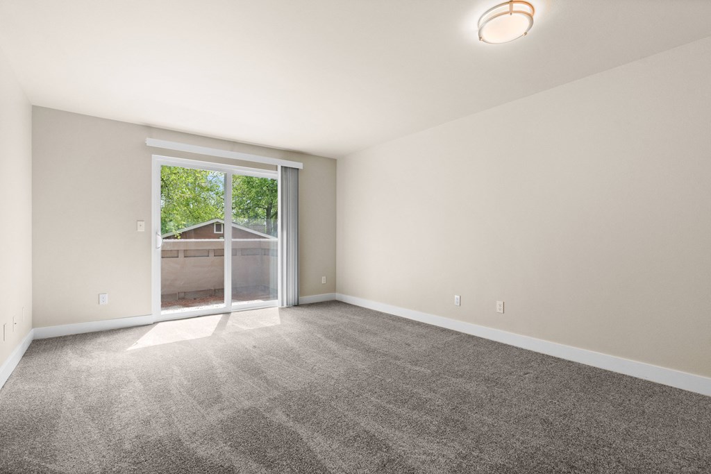 an empty living room with a large window and carpet