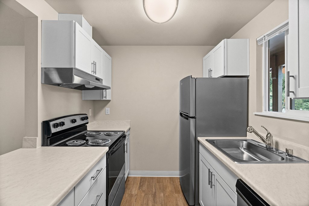 a kitchen with white cabinets and black appliances and a stainless steel refrigerator