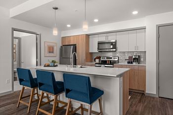 a kitchen with a large island with three blue chairs at Gage On Sixth, Tacoma, 98406