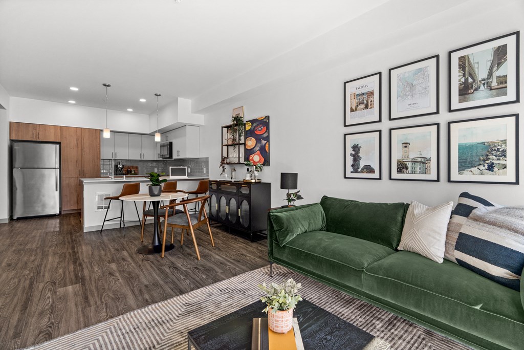 a living room with a green couch and a kitchen with a table and chairs at Gage On Sixth, Tacoma, 98406