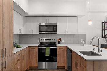 a kitchen with white cabinets and a stove and a sink at Gage On Sixth, Tacoma, WA