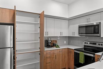 a kitchen with white cabinets and a black stove and a refrigerator at Gage On Sixth, Tacoma, 98406