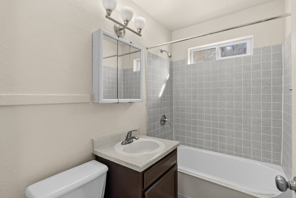 A bathroom with a white toilet, a sink, and a bathtub.