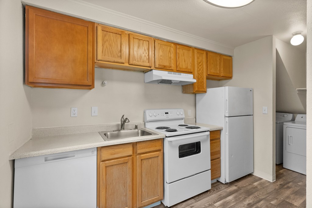 A kitchen with white appliances and wooden cabinets.