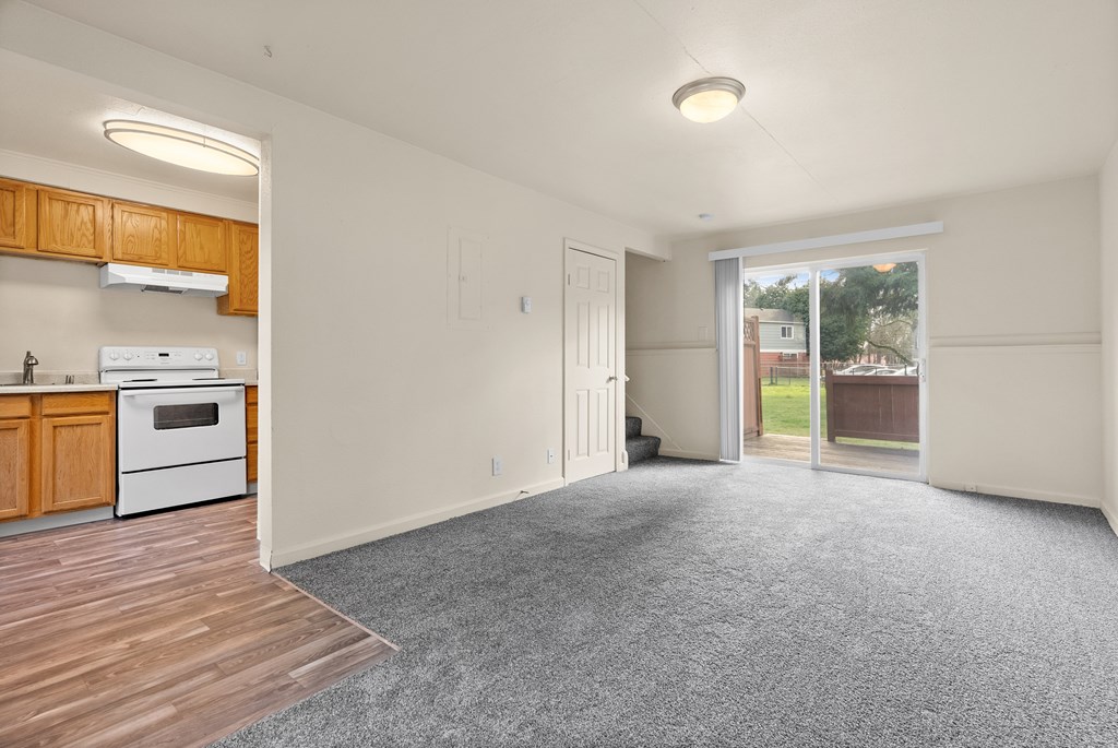 A large empty room with a kitchen area to the left.