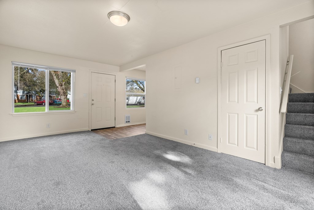 A room with a carpeted floor and a staircase leading to another room.