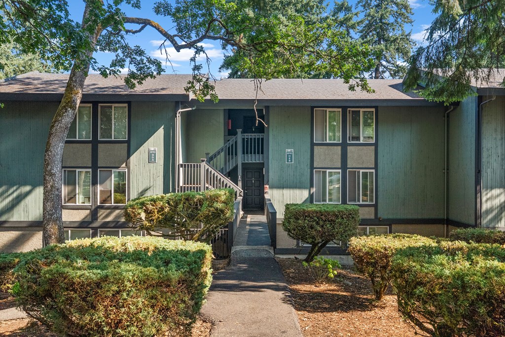 A green building with a tree in front.