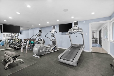 A spacious gym with a variety of equipment including treadmills, stationary bikes, and weight machines.