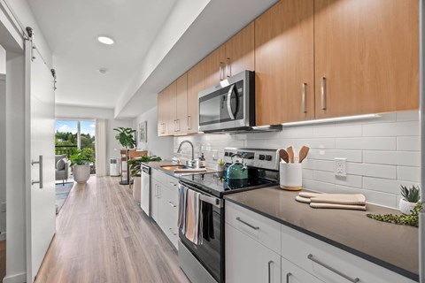 A modern kitchen with white cabinets and a black countertop.