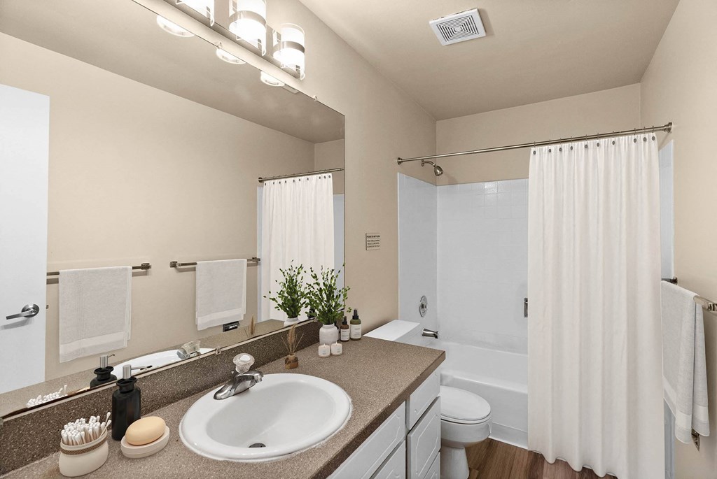 A bathroom with a sink, mirror, and shower.