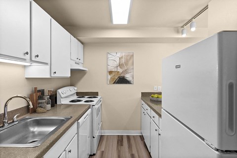 A kitchen with white cabinets and a white fridge.